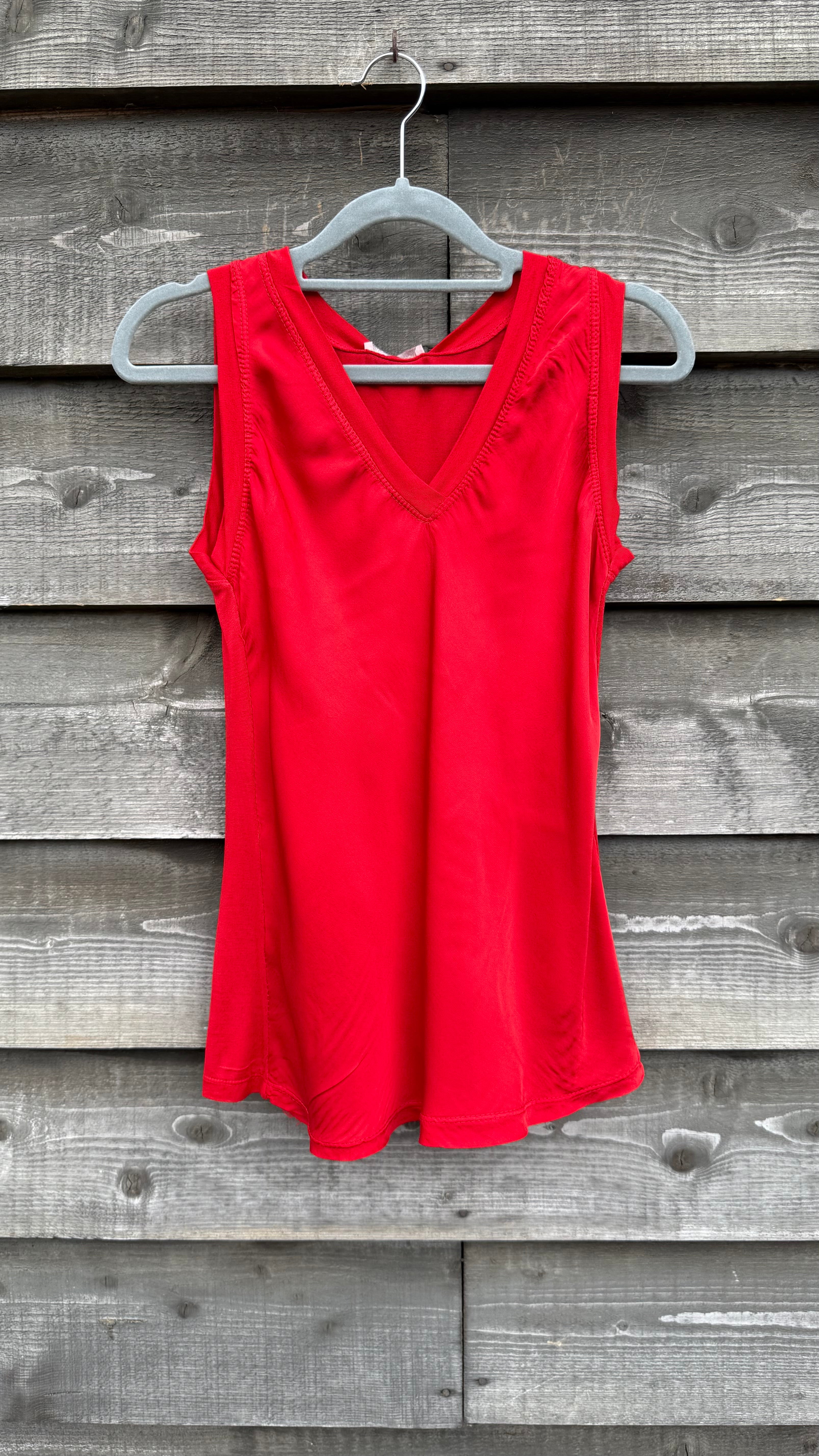 Red sleeveless top on a hanger against a wooden background