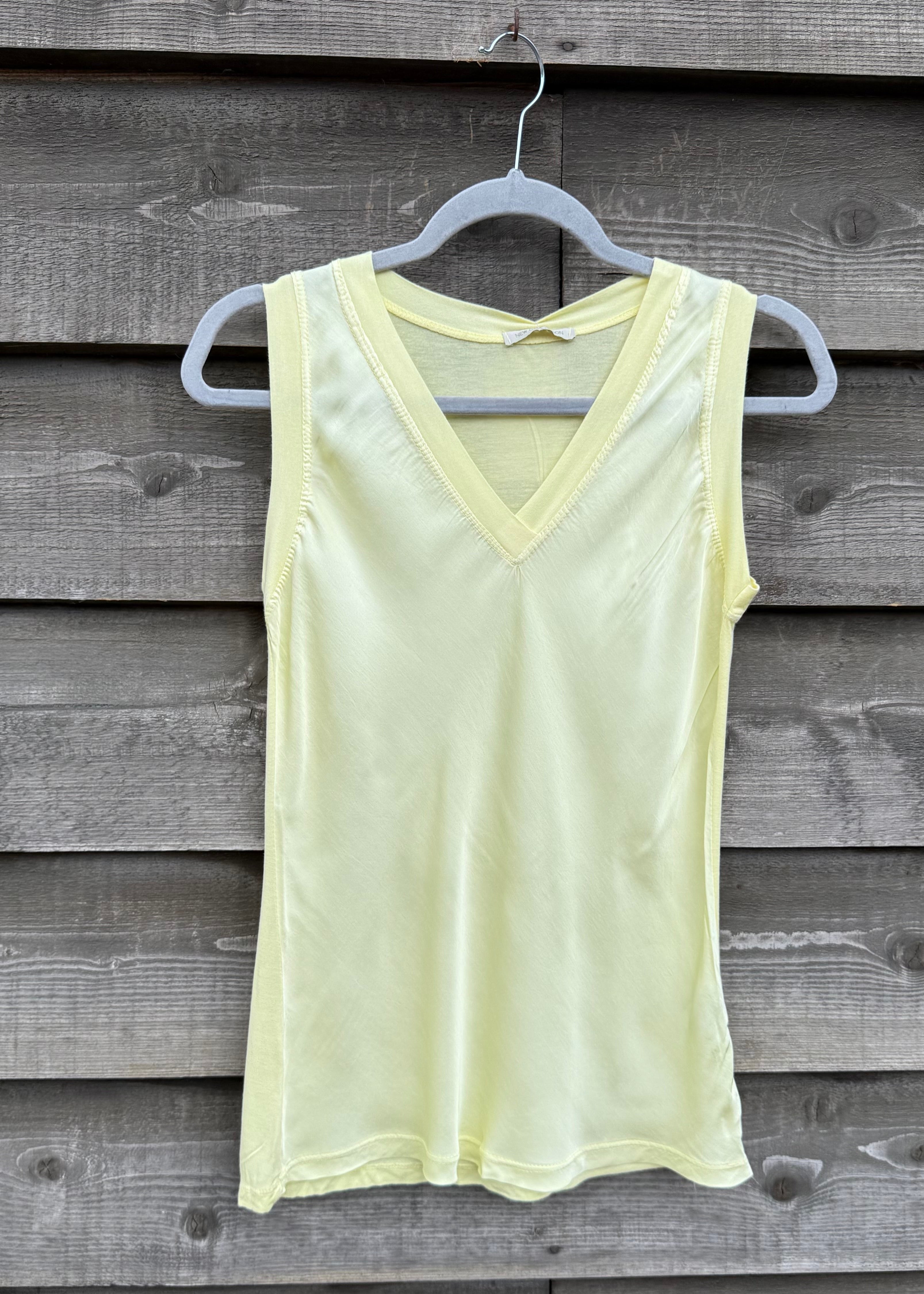 Light yellow tank top hanging on a wooden wall