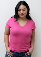Woman wearing a bright pink t-shirt against a plain background