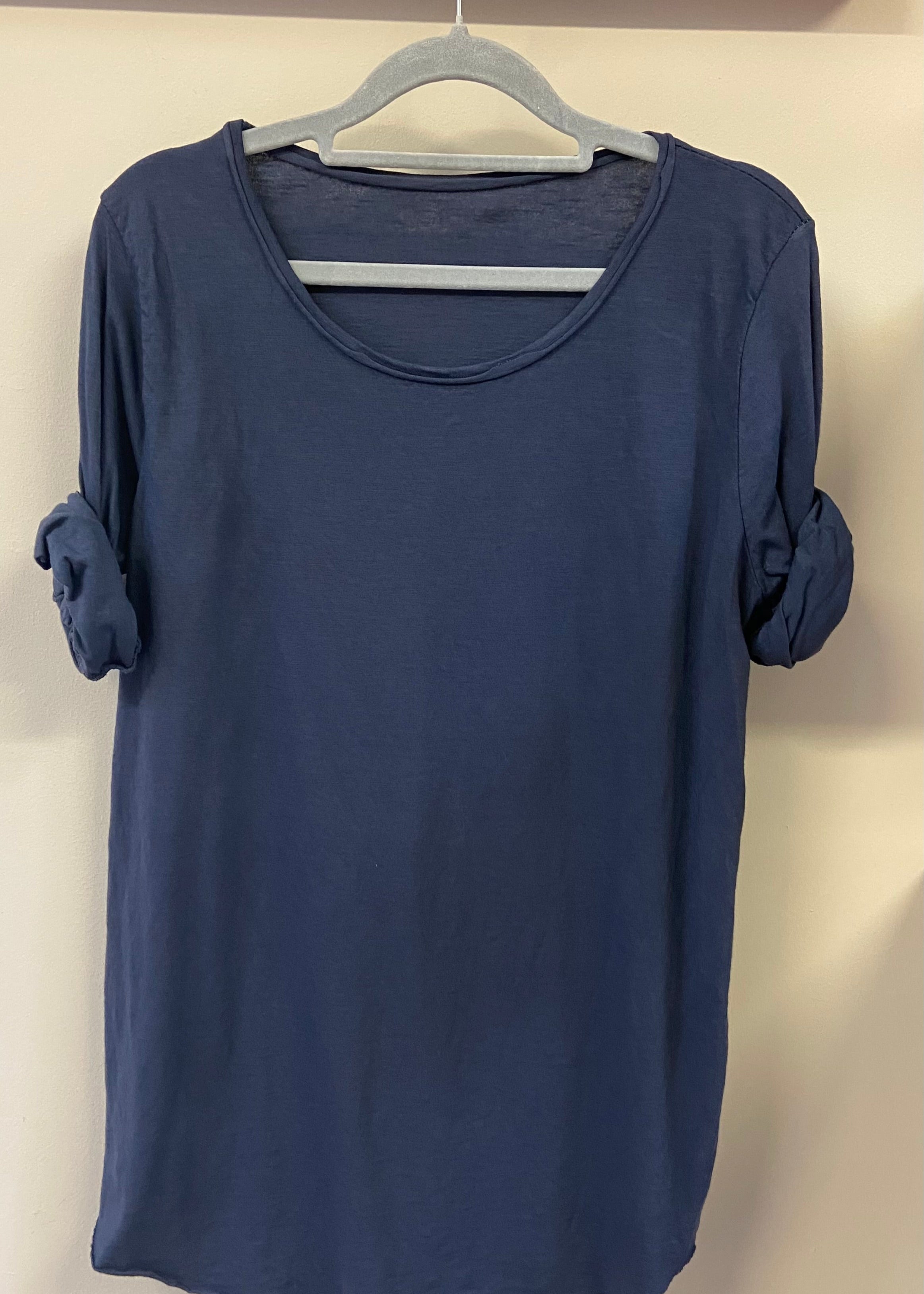 A woman wearing a light blue, long-sleeved cotton top with curved raw edges, in a loose fit style.