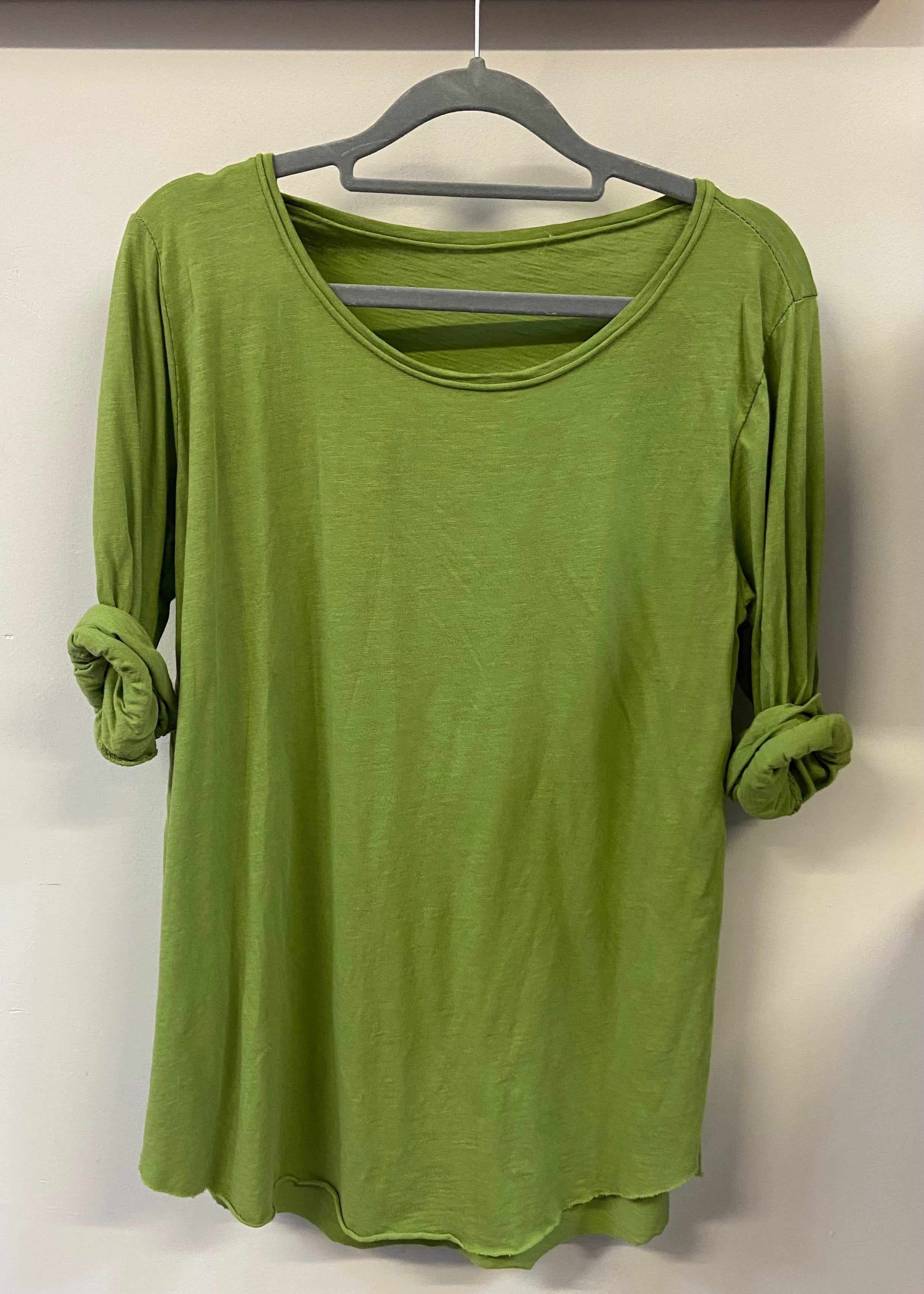 A woman wearing a light blue, long-sleeved cotton top with curved raw edges, in a loose fit style.