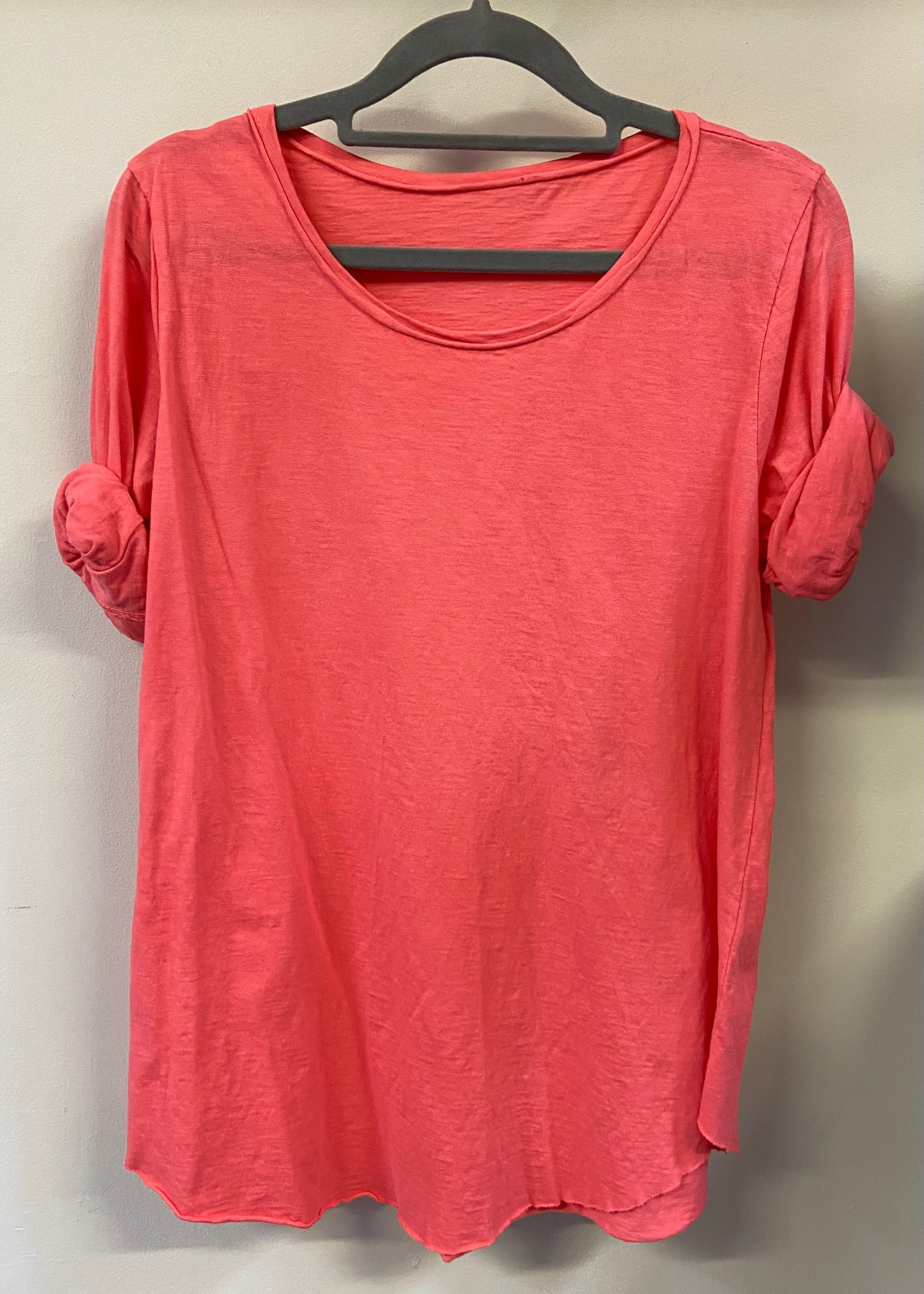 A woman wearing a light blue, long-sleeved cotton top with curved raw edges, in a loose fit style.