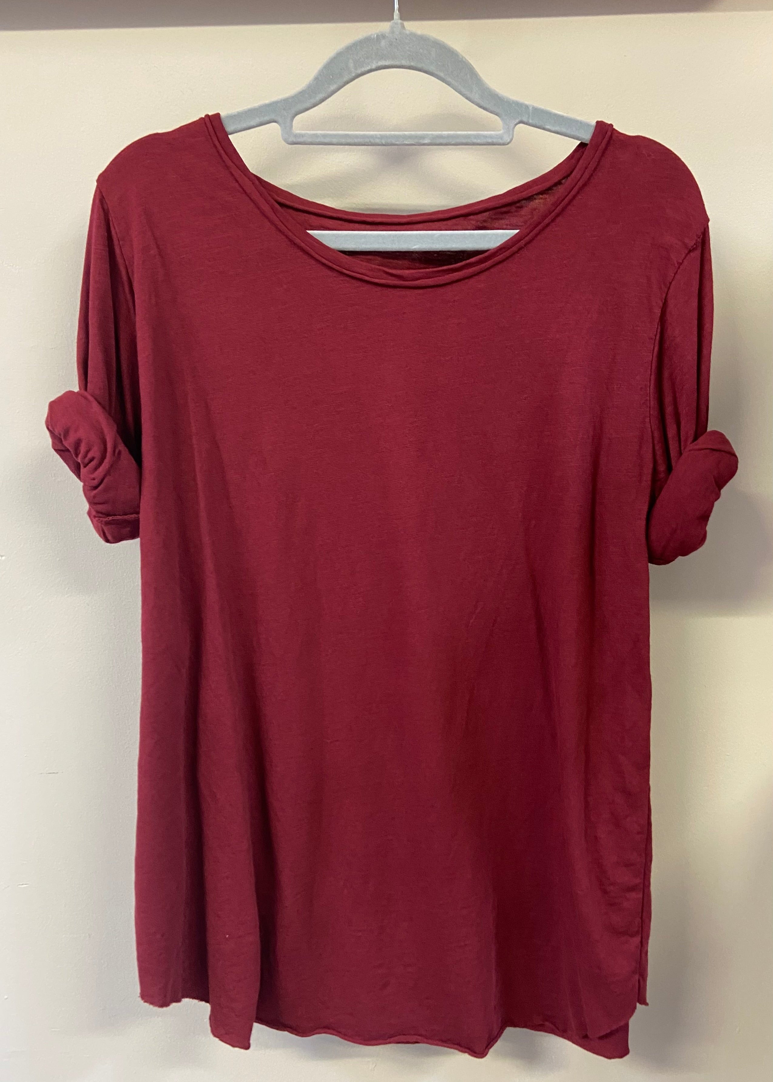 A woman wearing a light blue, long-sleeved cotton top with curved raw edges, in a loose fit style.