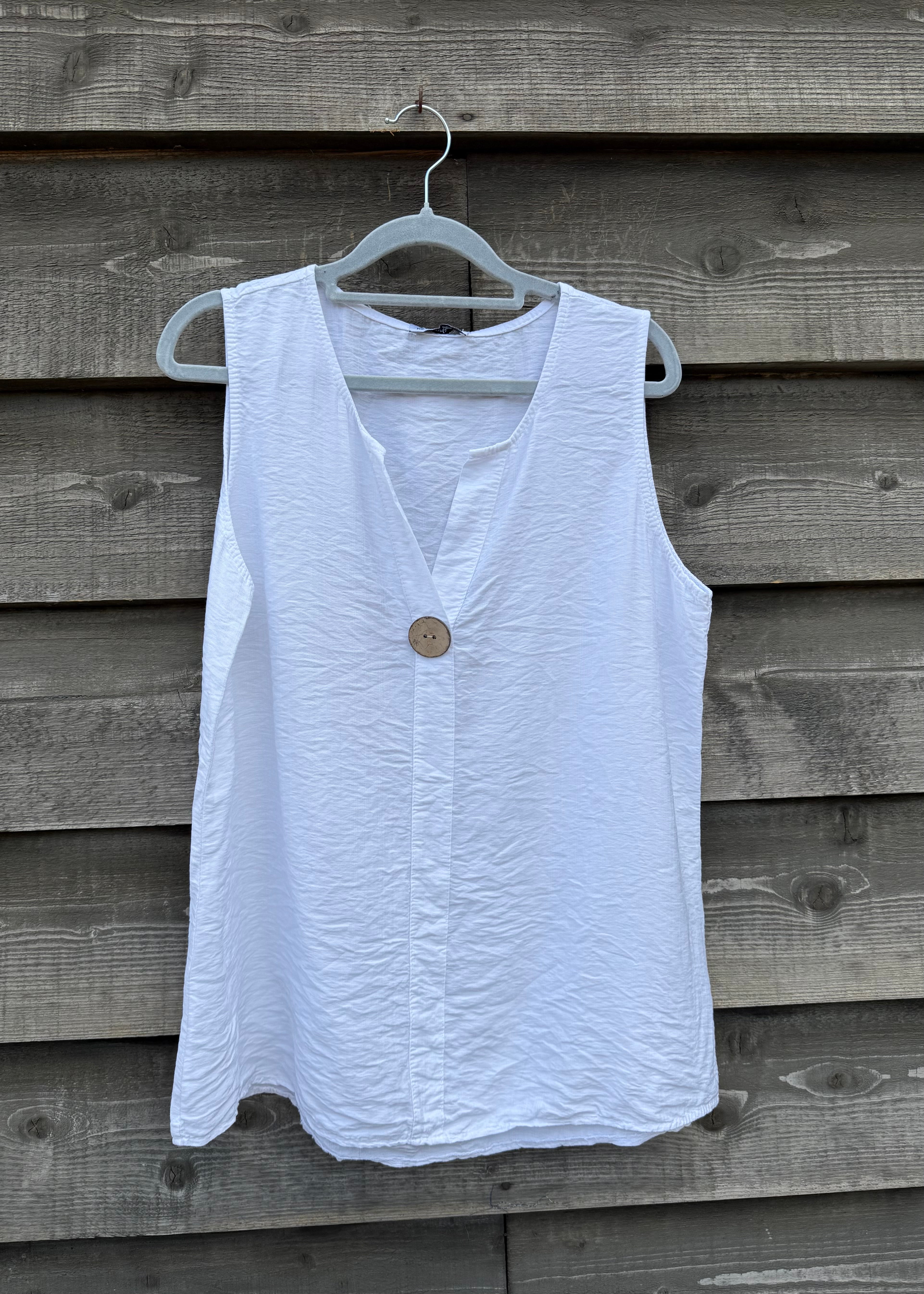 White sleeveless top with a button on a wooden background