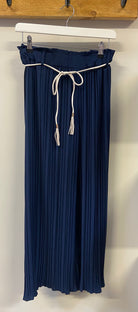 A person wearing yellow pleated trousers with a denim jacket and white shoes.