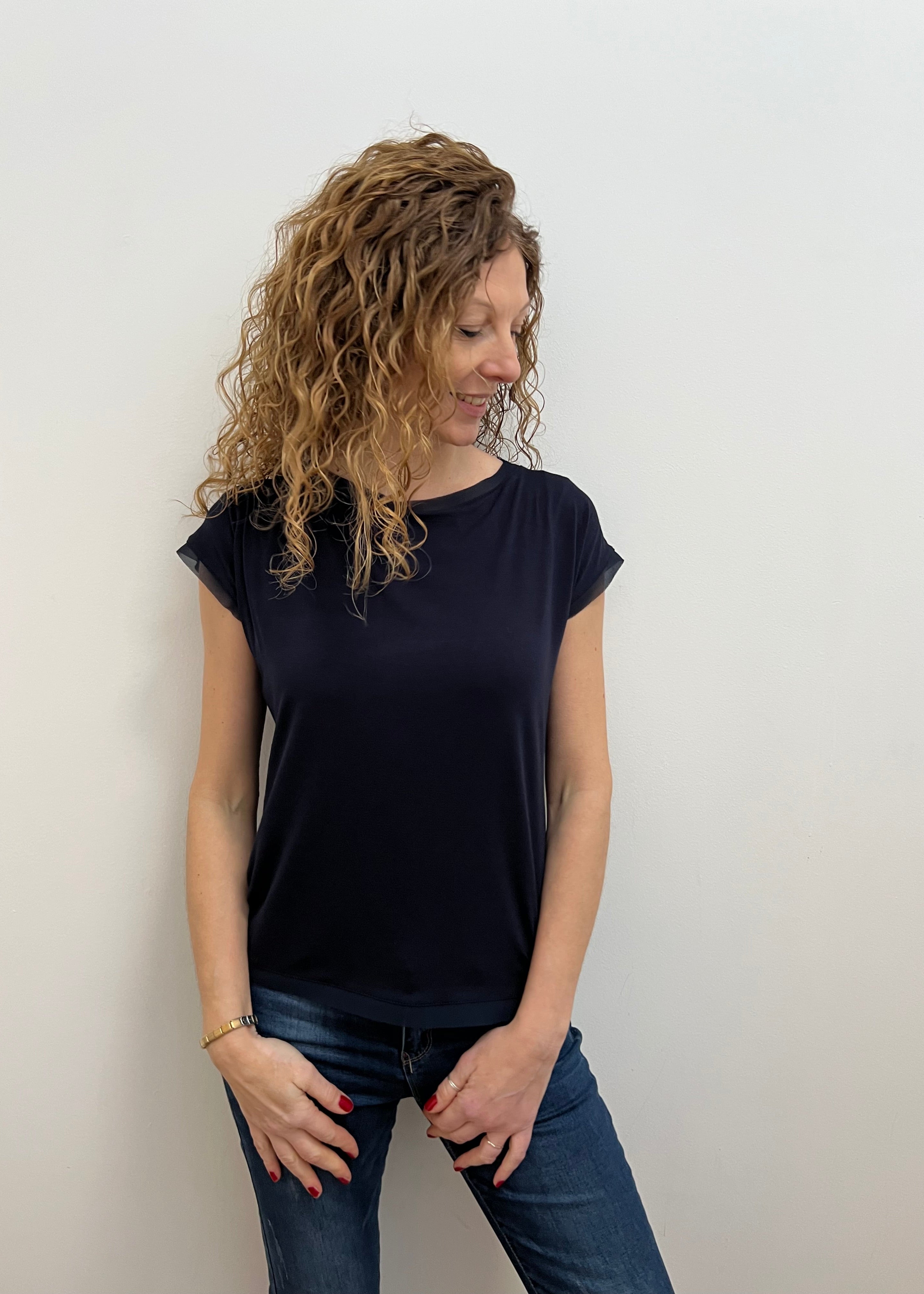 Woman wearing a dark blue top and jeans on a white background