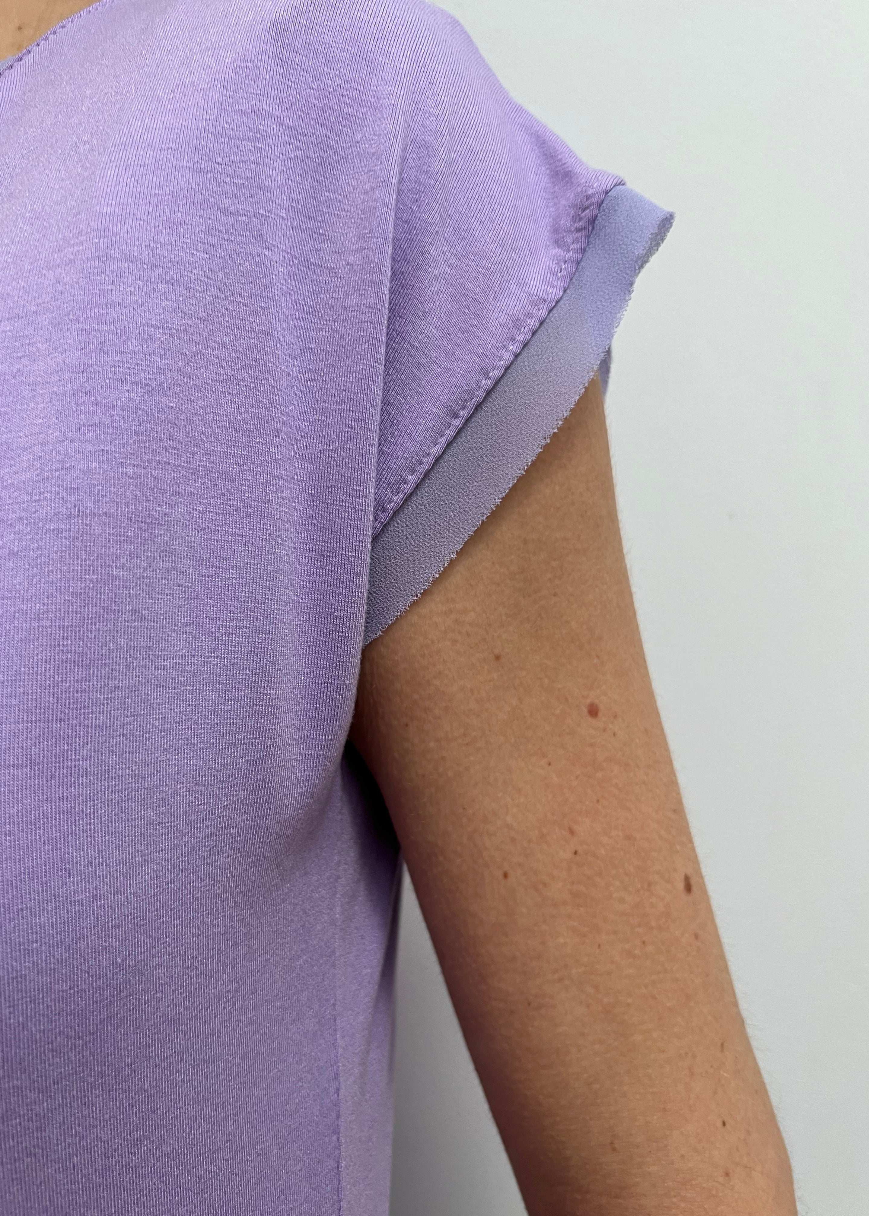 Close-up of a person wearing a light purple shirt against a plain background