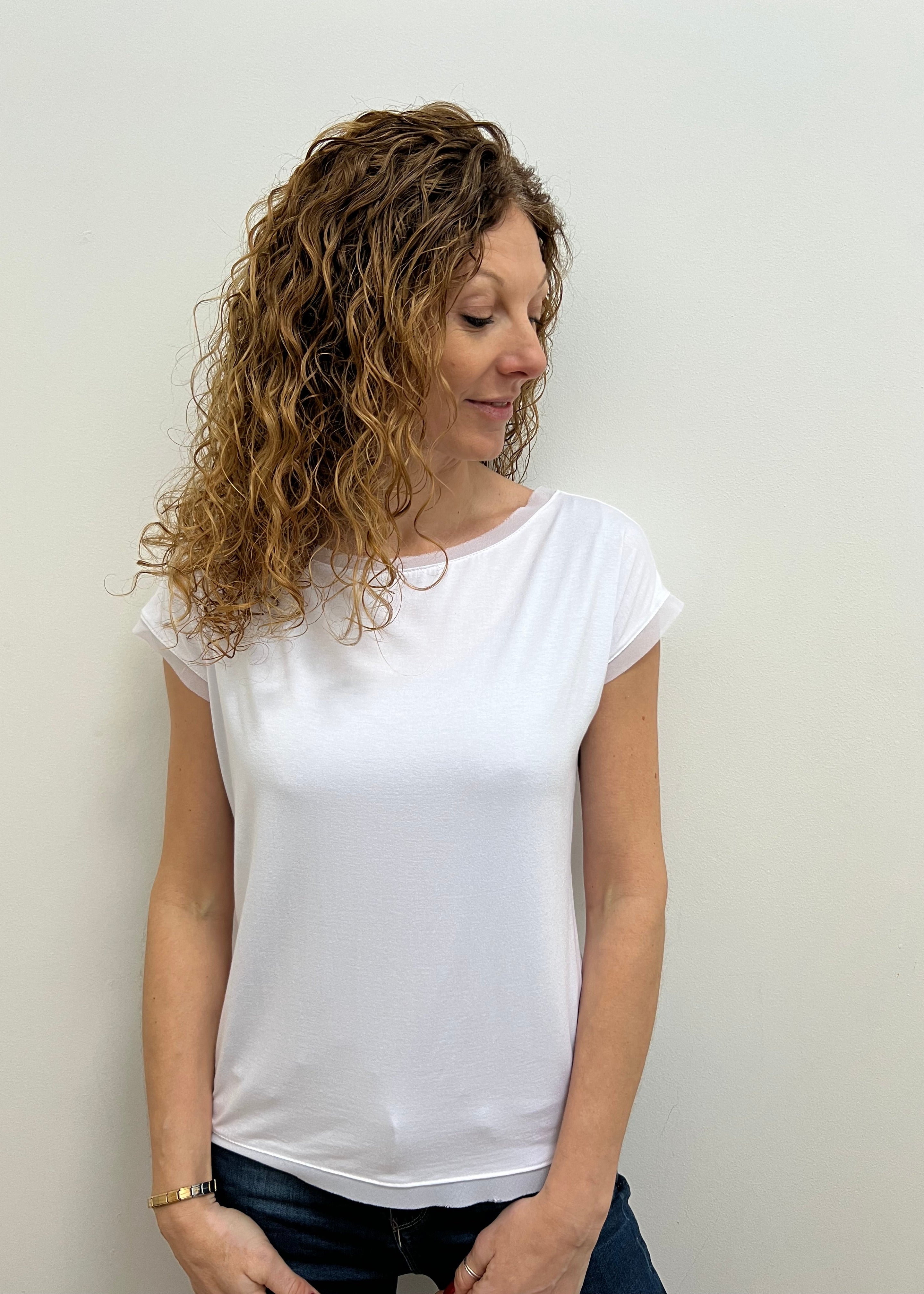 A person wearing a white, short-sleeved Strati viscose t-shirt.