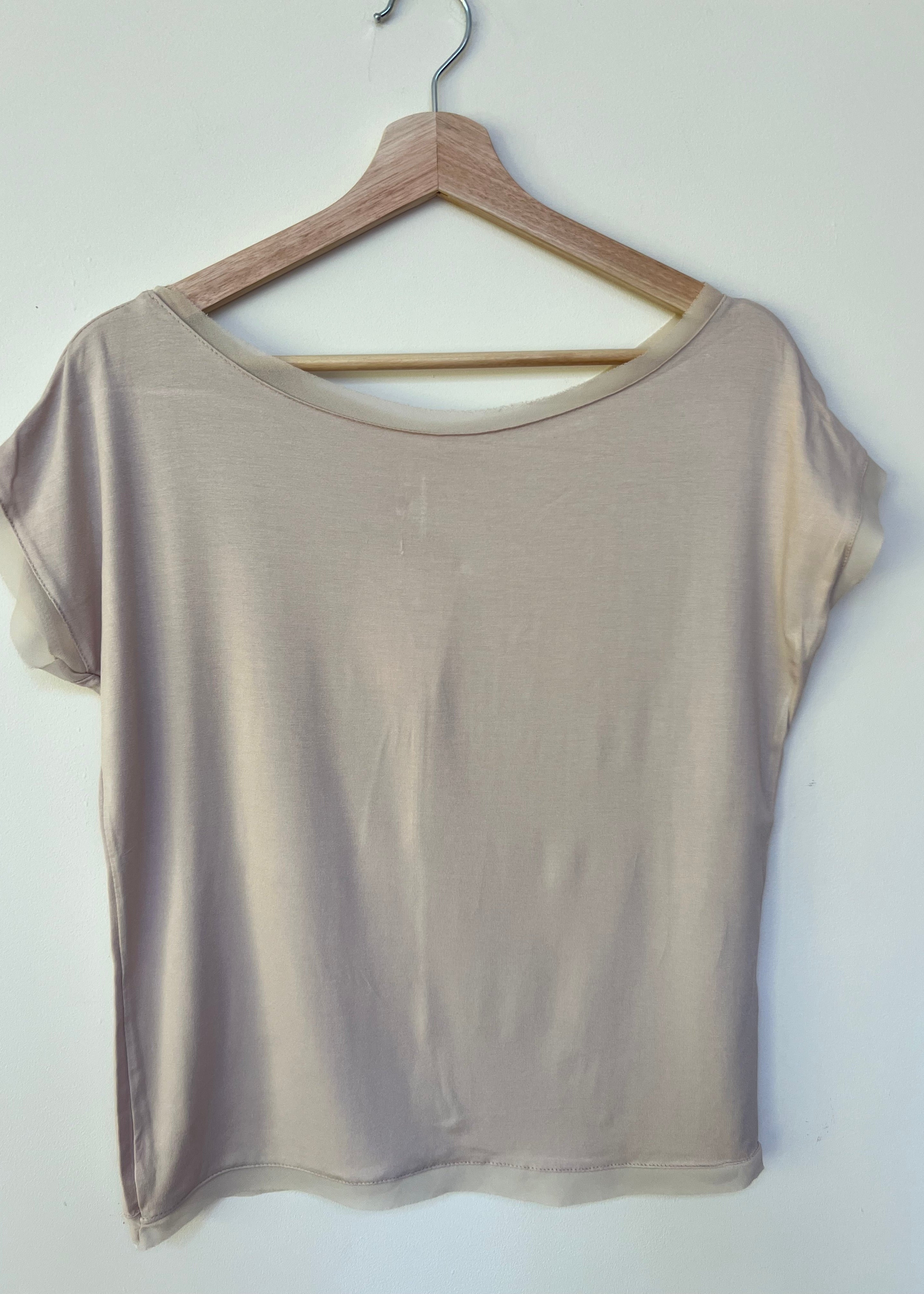 A woman wearing a white short-sleeved t-shirt with a slightly fitted style, standing against a plain background.