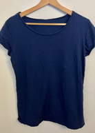 Navy blue t-shirt on a wooden hanger against a white background