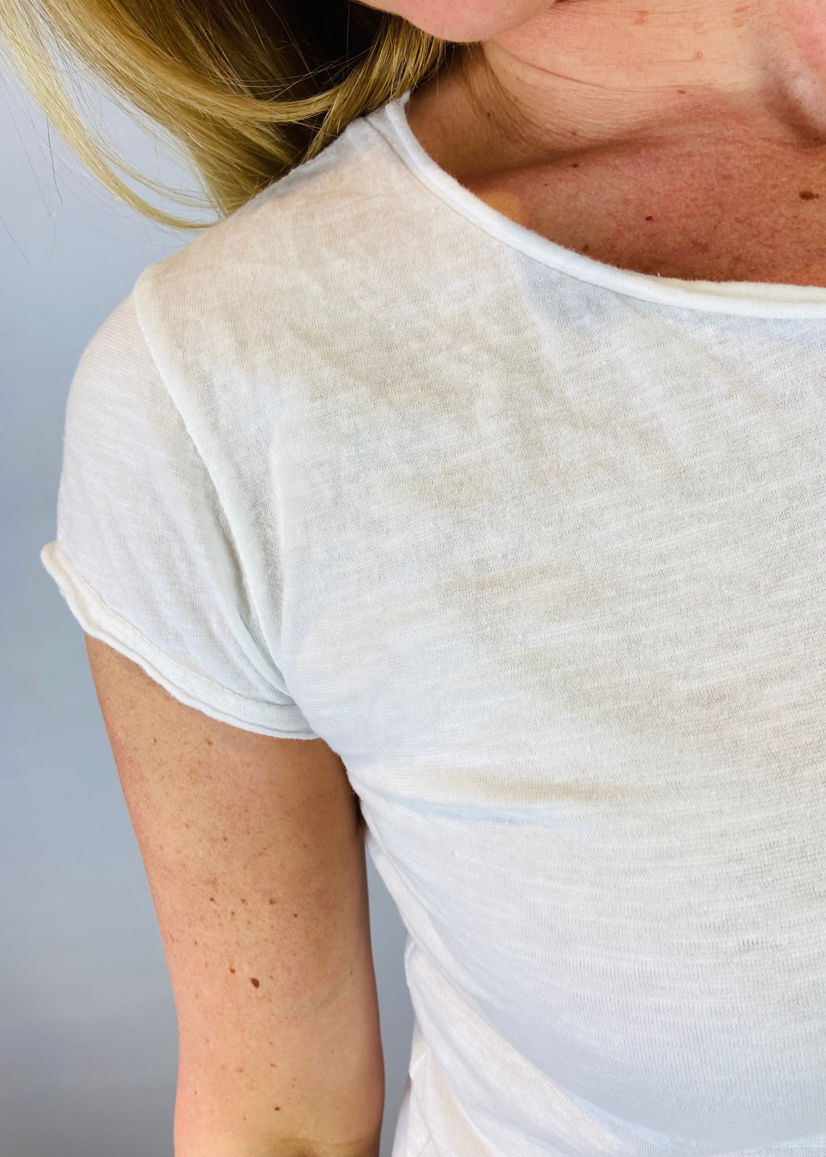 Close-up of a person wearing a white t-shirt against a plain background